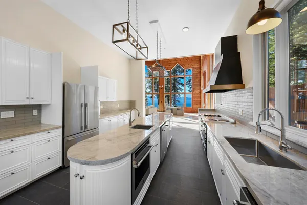 a large kitchen with stainless steel appliances kitchen island granite countertop a sink a stove a counter space and cabinets