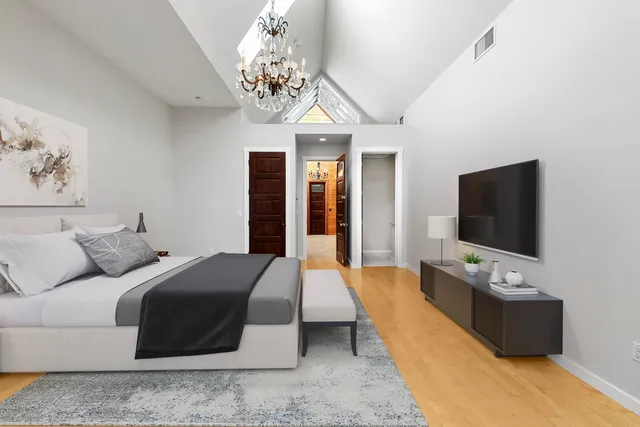 a spacious bedroom with a balcony a bed and a chandelier