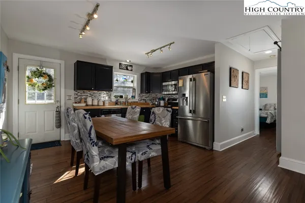 a kitchen with stainless steel appliances granite countertop a refrigerator a stove a microwave a dining table and chairs with wooden floor