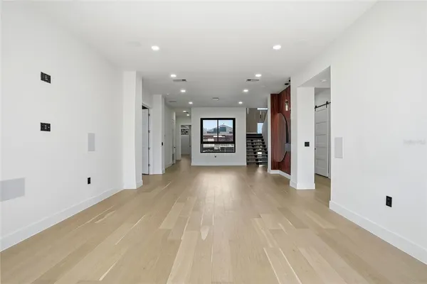 a view of an empty room with wooden floor and a ceiling fan
