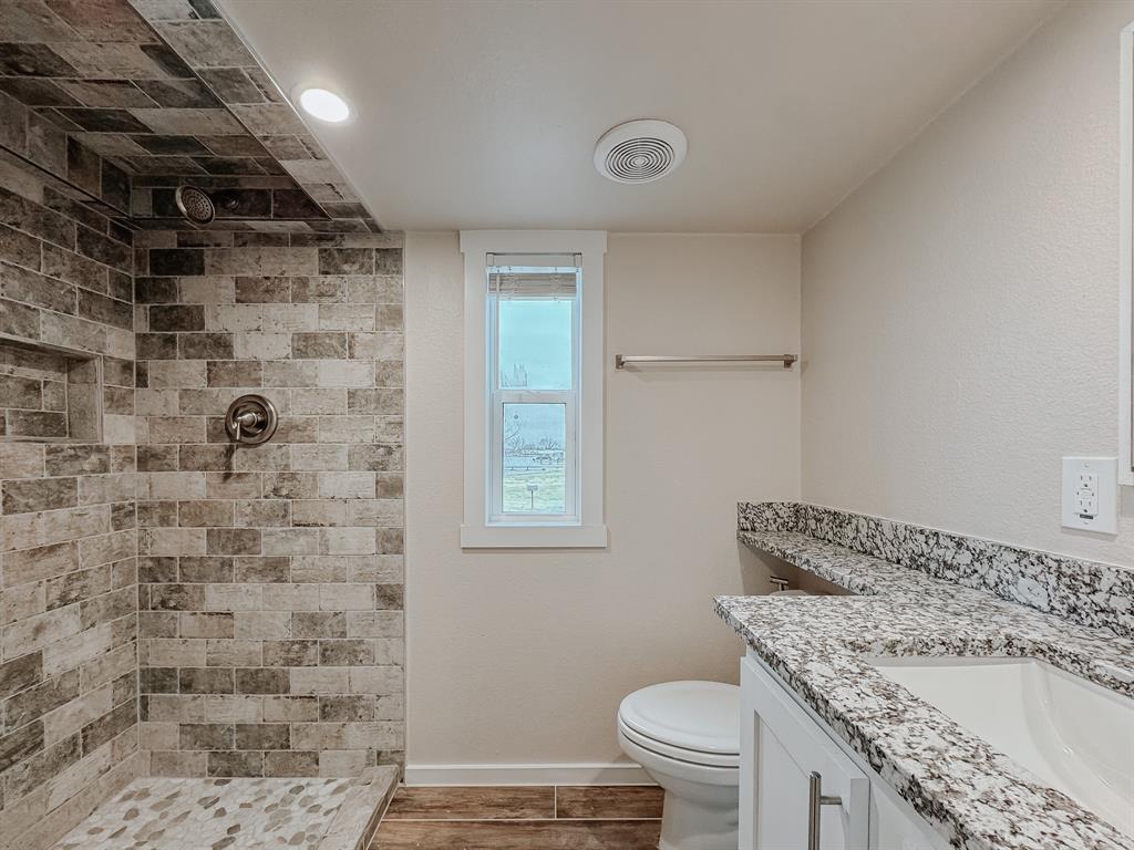 6422 Peninsula Road Kerens, TX 75144 - Photo 6 of 16 a bathroom with a granite countertop toilet a sink and a shower