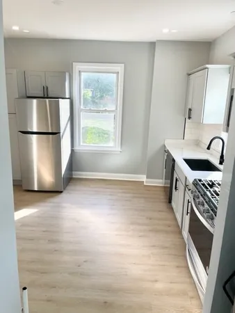 a kitchen with stainless steel appliances granite countertop a refrigerator a sink a stove and a wooden floors