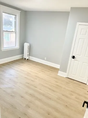 an empty room with wooden floor and window