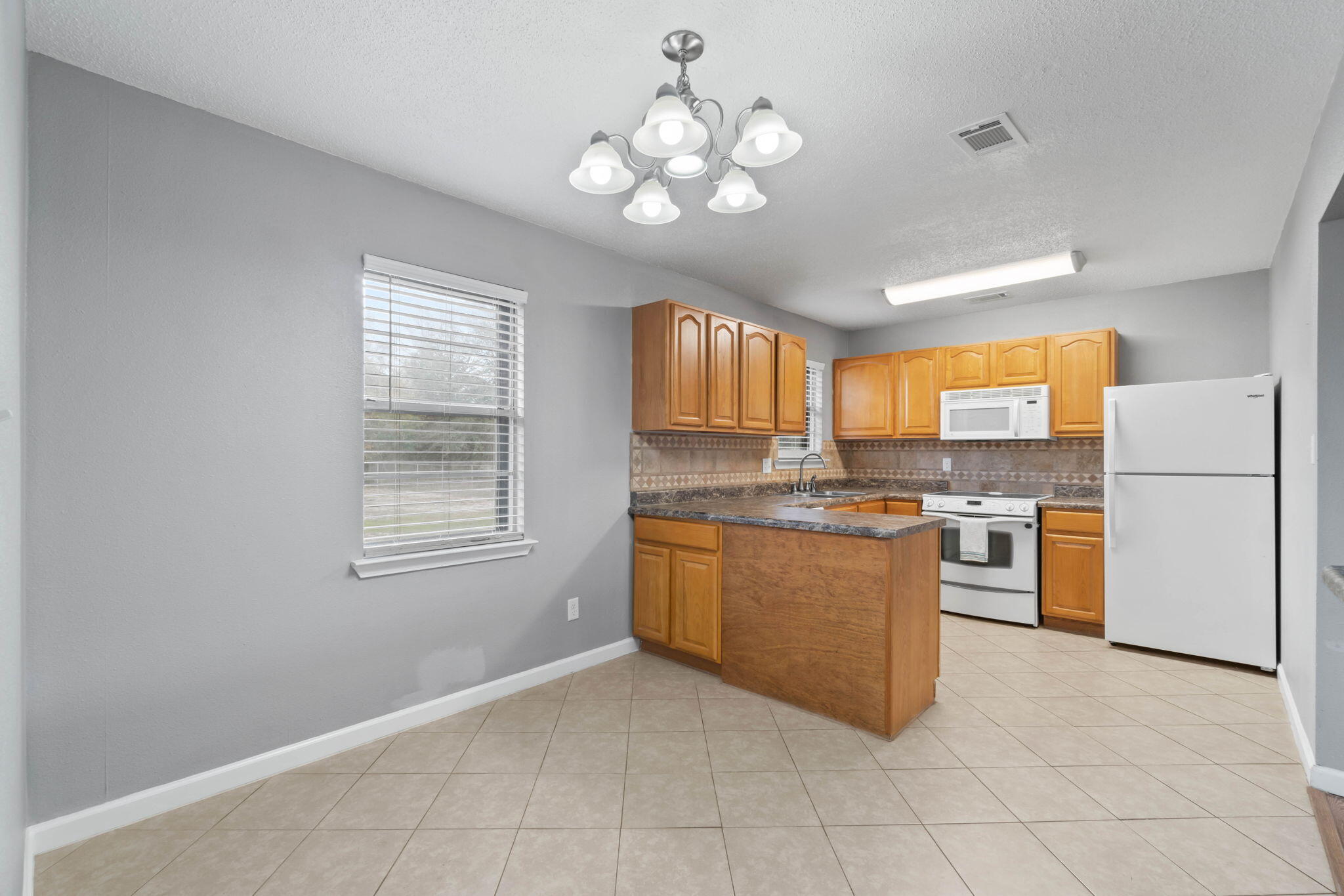 3545 Poverty Creek Road Crestview, FL 32539 - Photo 14 of 33 a kitchen with stainless steel appliances granite countertop a refrigerator a sink dishwasher a dining table and chairs with wooden floor