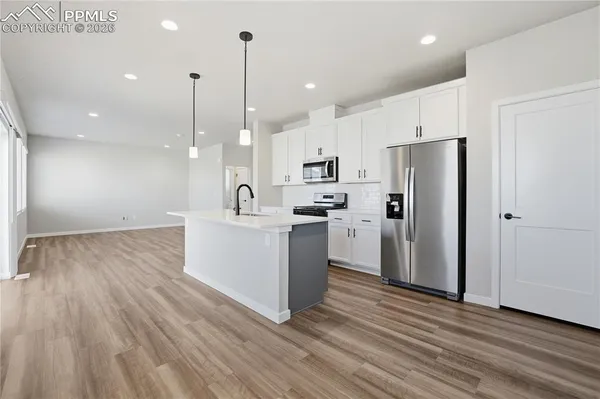 a kitchen with a refrigerator a sink and white cabinets with wooden floor