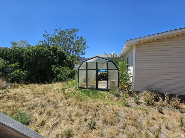 52 Quail Court Moab, UT 84532 - Photo 36 of 36 Greenhouse structure with translucent panels and a dark frame, positioned within a grassy area