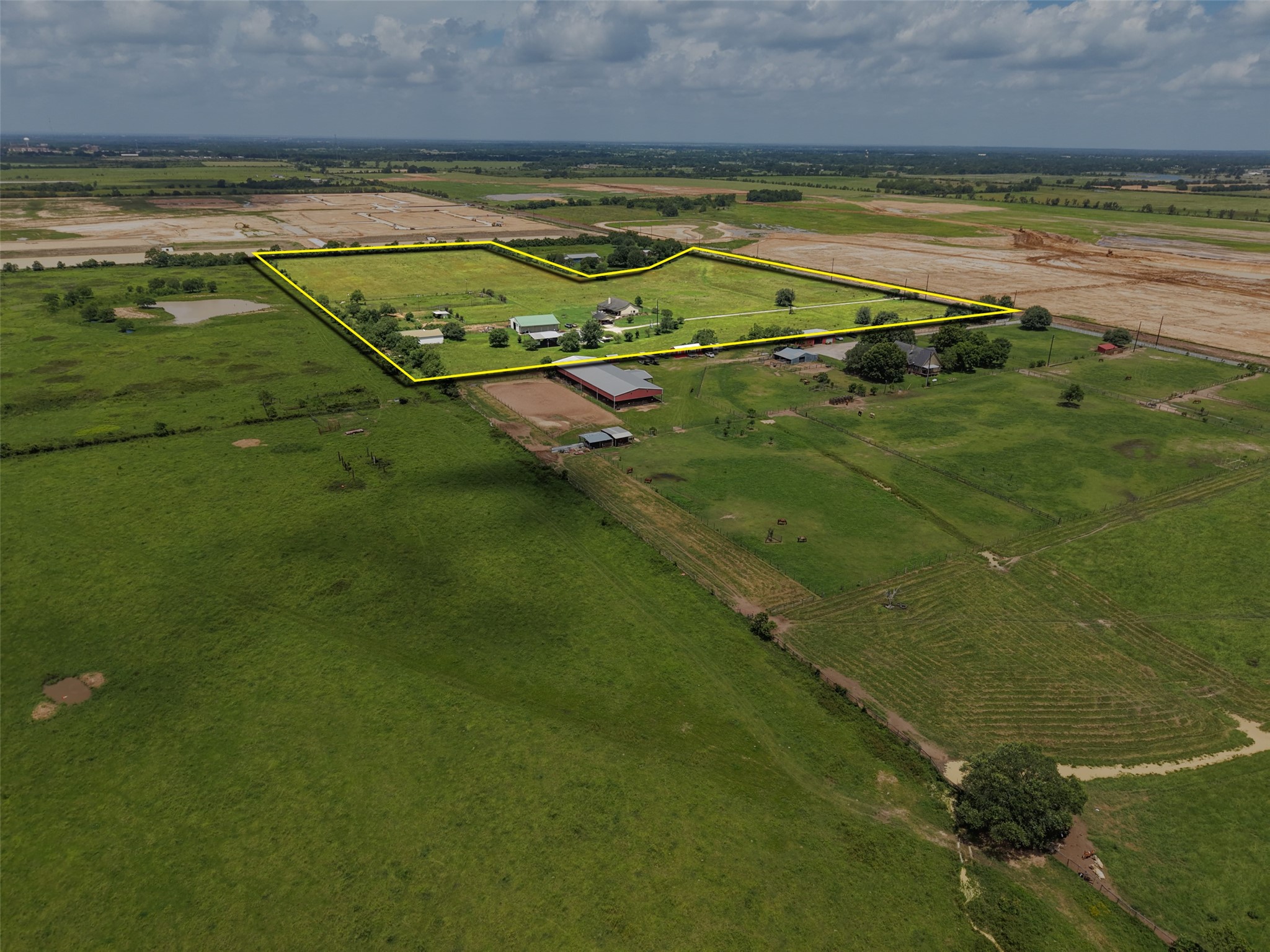33737 Cameron Road Waller, TX 77484 - Photo 19 of 24 This aerial view showcases a sprawling rural property with green pastures, multiple barns, and residential buildings. The expansive land is ideal for farming or equestrian activities, offering a serene countryside setting.
