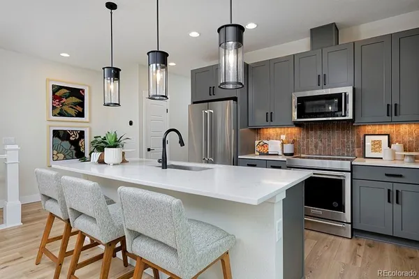 a kitchen with stainless steel appliances a stove a sink a microwave a refrigerator and cabinets