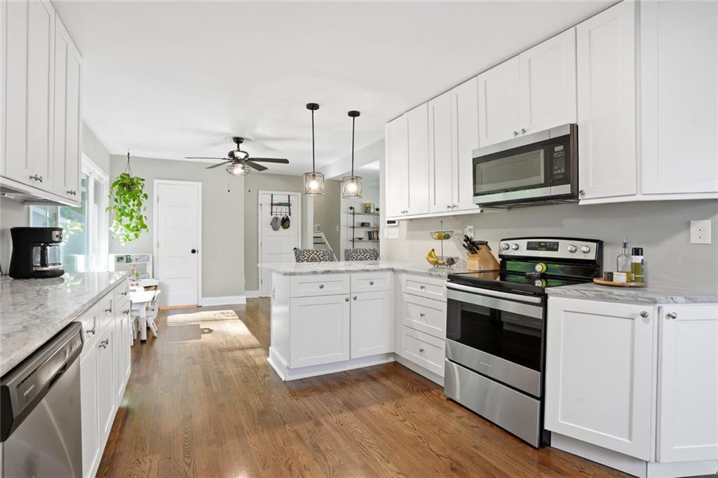 1430 Thomas Road Decatur, GA 30030 - Photo 11 of 42 a kitchen with stainless steel appliances white cabinets a sink a stove a microwave and wooden floors