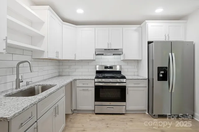 a kitchen with stainless steel appliances a refrigerator sink and stove top oven