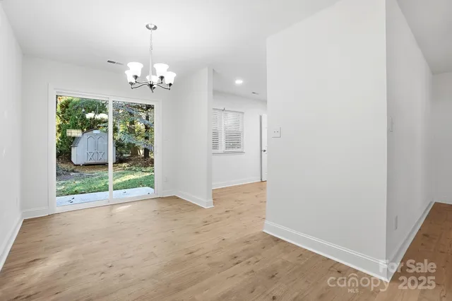an empty room with wooden floor and chandelier