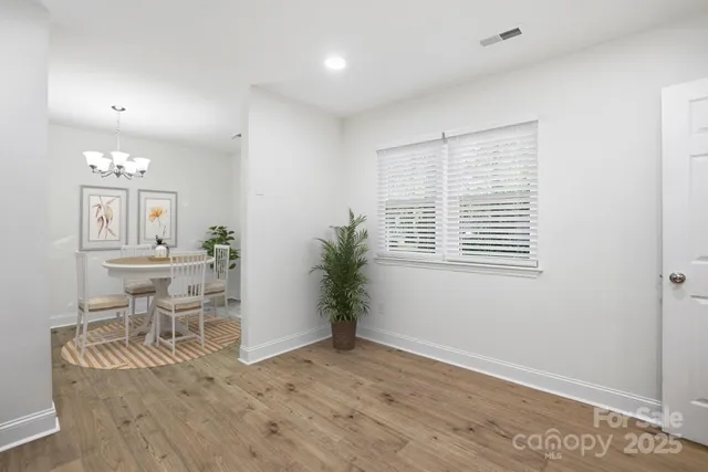 a dining room with wooden floor a chandelier a wooden table and chairs