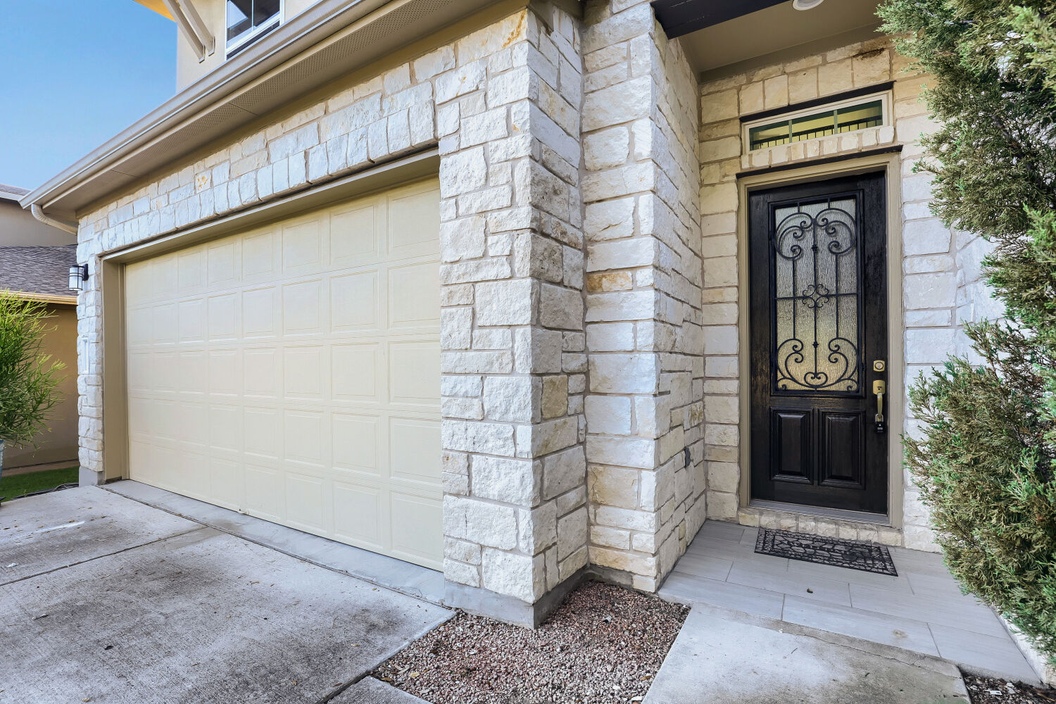 5821 Buchanan Draw Road Austin, TX 78738 - Photo 3 of 29 A cream-colored garage door and wrought iron-detailed entry door define this inviting home's stone facade.
