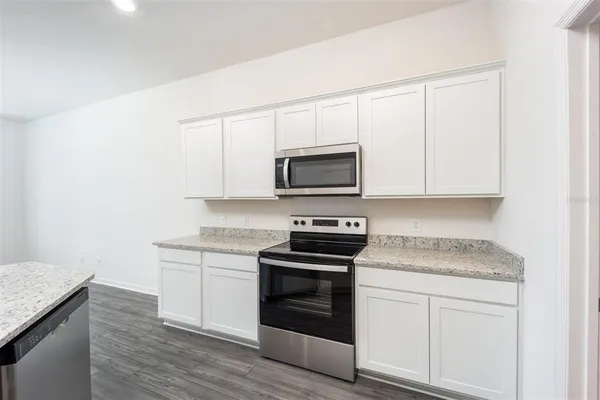 a kitchen with granite countertop white cabinets and stainless steel appliances