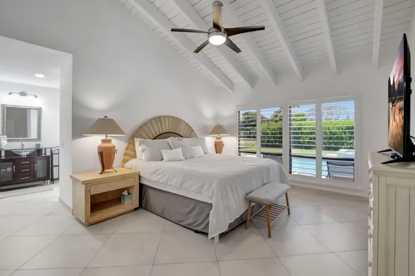 a spacious bedroom with a bed a large window and flat screen tv