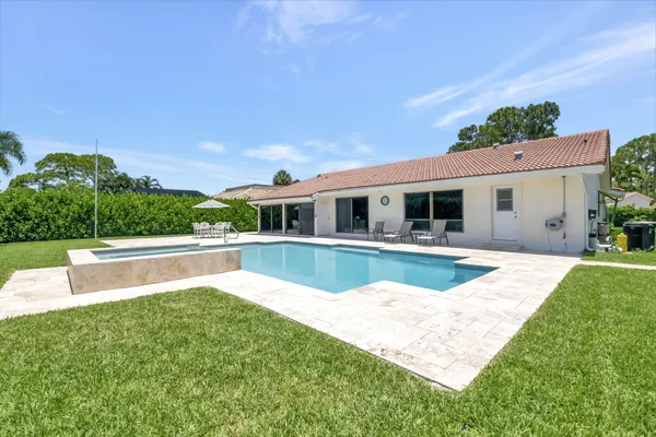 a view of house with swimming pool and a yard