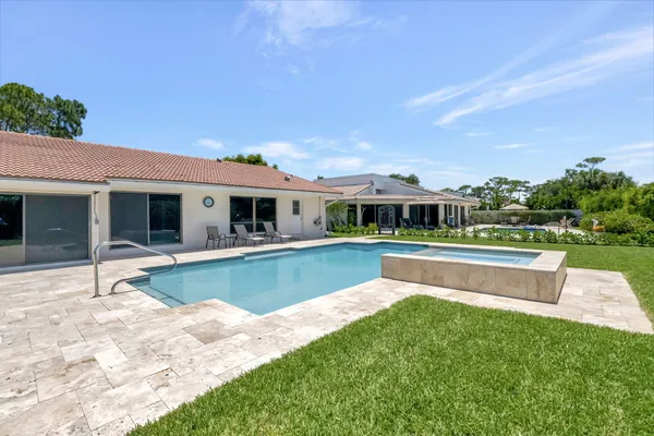 a view of house with swimming pool and a yard