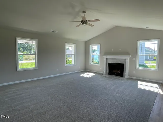 an empty room with windows and fireplace