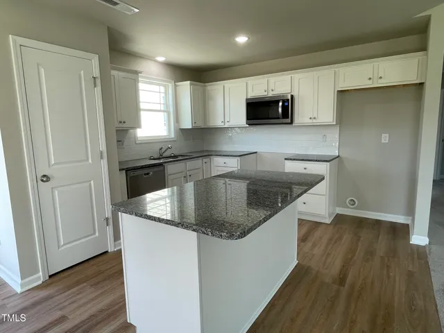 a kitchen with stainless steel appliances granite countertop a sink a microwave a refrigerator and grey cabinets