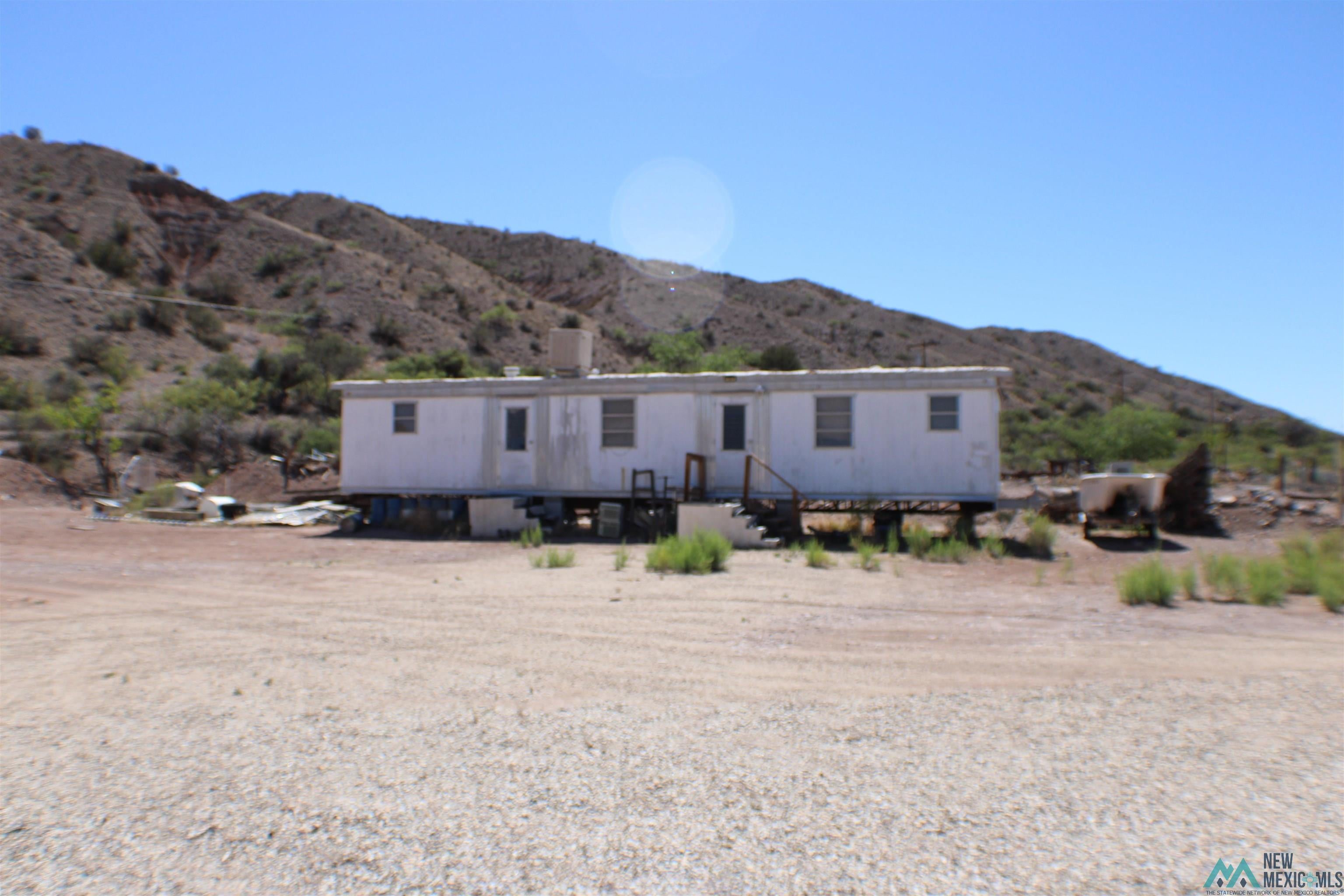 334 Animas Creek Road Caballo, NM 87931 - Photo 18 of 20 Mobile home with a white exterior and multiple windows, situated on a gravel lot