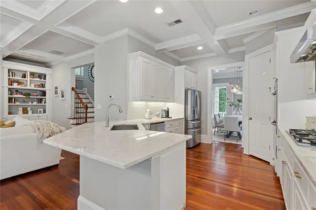 a living room with stainless steel appliances furniture a rug kitchen view and a large window