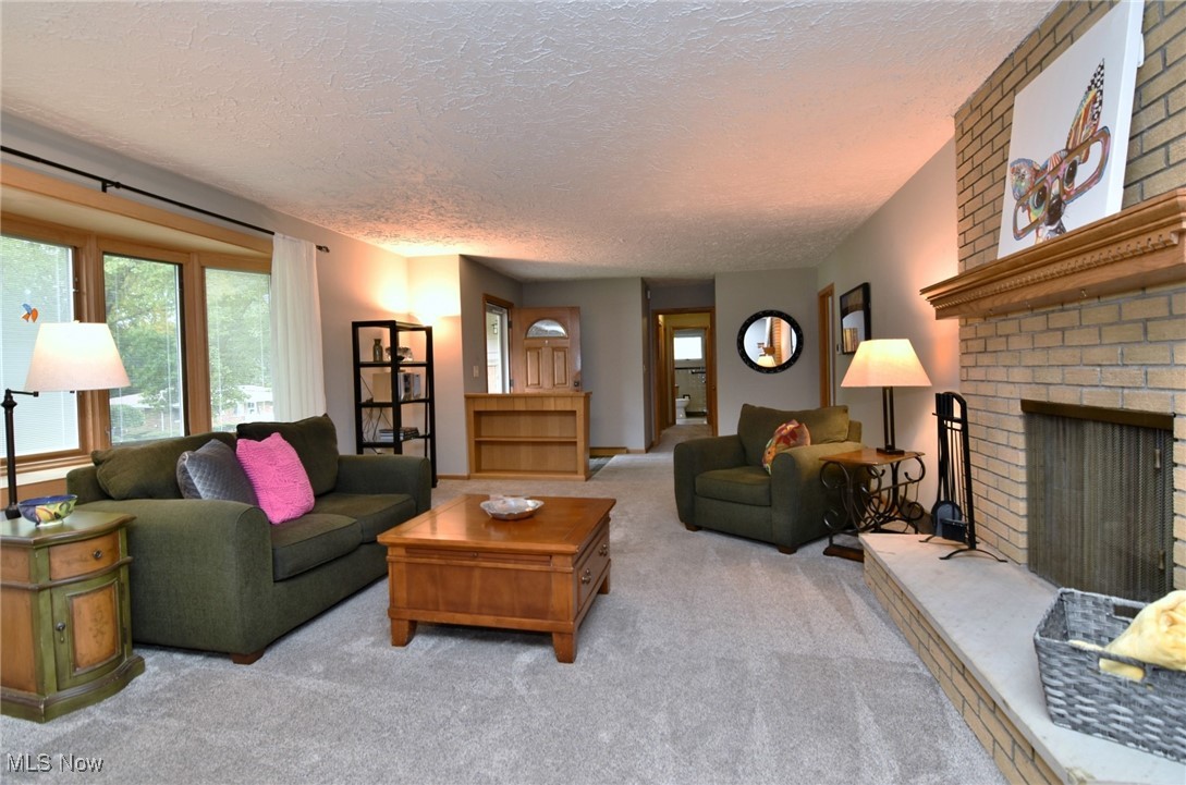 2071 Wyndham Road Akron, OH 44313 - Photo 5 of 42 Living room featuring a brick fireplace, a textured ceiling, and light carpet.
