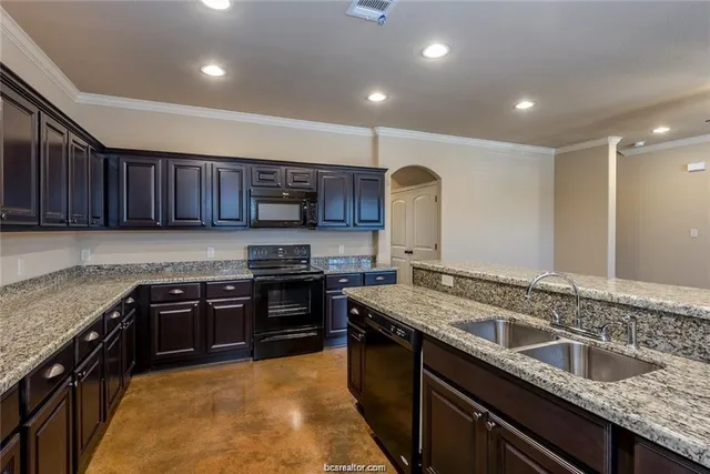 a kitchen with stainless steel appliances granite countertop wooden cabinets a stove a sink and a oven