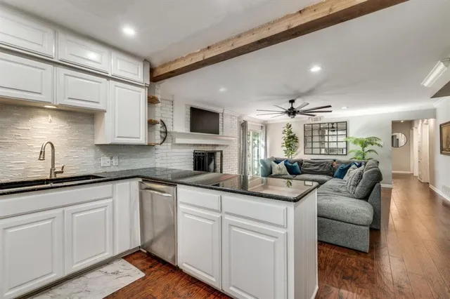 a open kitchen with granite countertop a sink and white cabinets