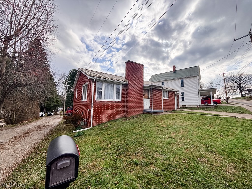 724 East Main Street Barnesville, OH 43713 - Photo 2 of 28 View of front of home with a chimney, brick siding, and a front yard