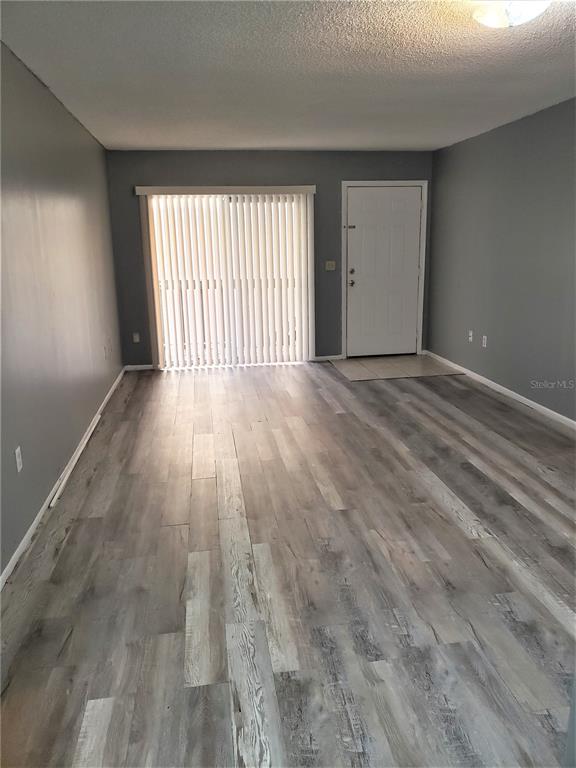 4151 South Semoran Boulevard, Unit 8 Orlando, FL 32822 - Photo 9 of 27 wooden floor in an empty room with a window