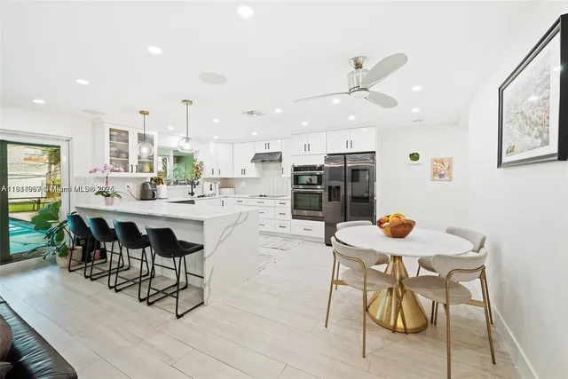 a kitchen with a dining table chairs and white cabinets