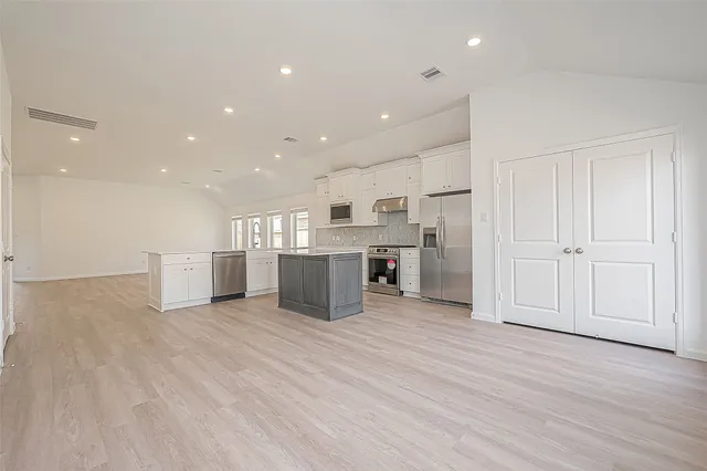 a kitchen with stainless steel appliances granite countertop white cabinets a refrigerator and a stove