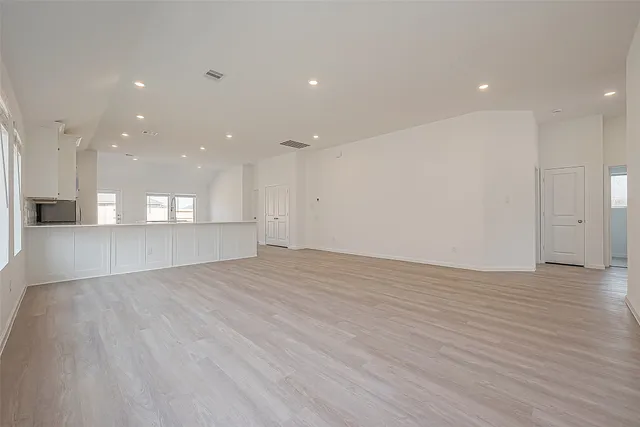 a view of an empty room with window and wooden floor
