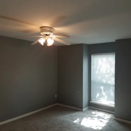 an empty room with windows and fan