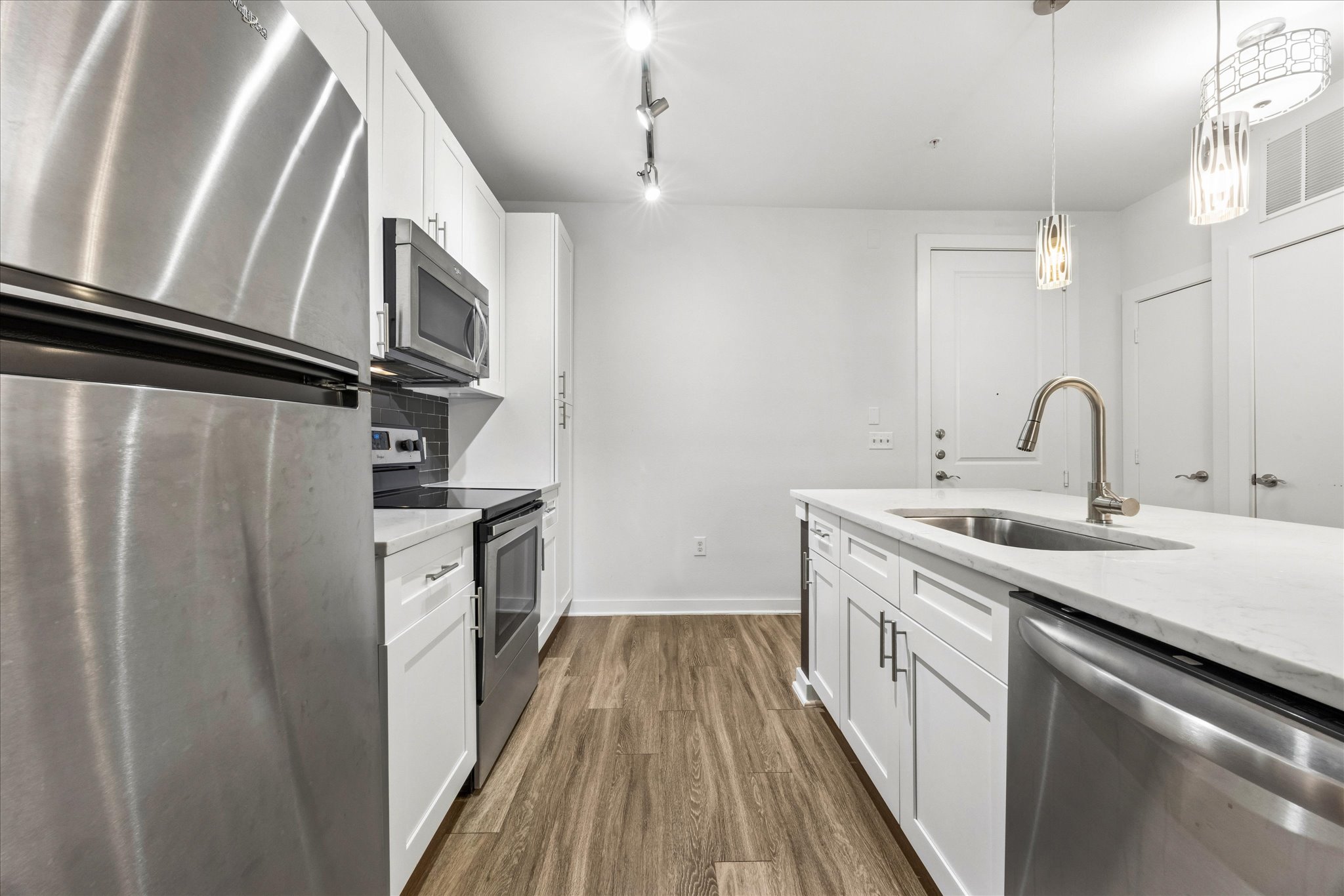 1900 Barton Springs Road, Unit 4041 Austin, TX 78704 - Photo 14 of 35 A contemporary kitchen features sleek white cabinetry and integrated stainless steel appliances.