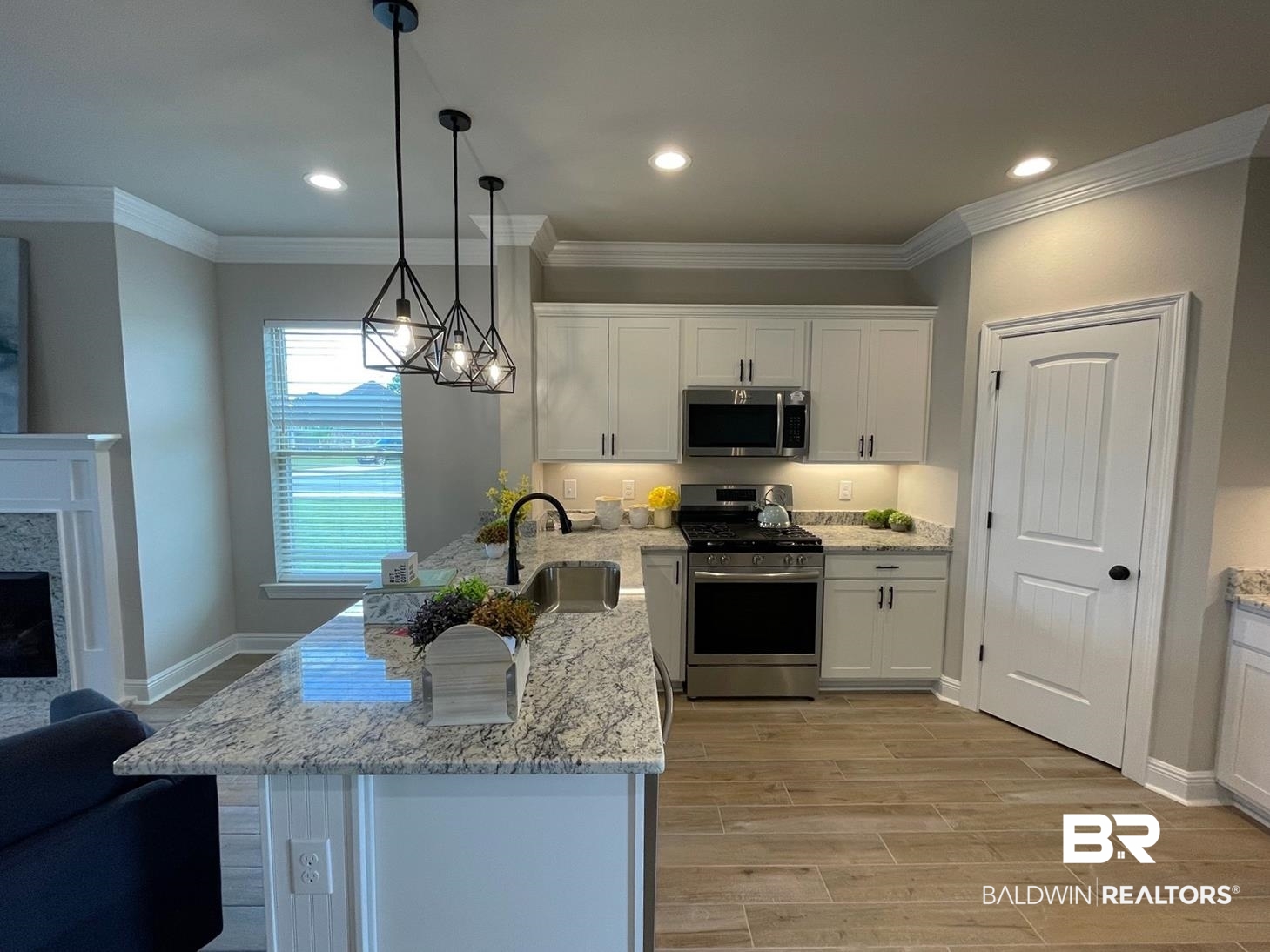 9961 Chipper Lane Foley, AL 36535 - Photo 2 of 16 Kitchen featuring white cabinetry, decorative light fixtures, a fireplace, light stone countertops, and appliances with stainless steel finishes