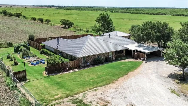 an aerial view of a house with big yard and large trees