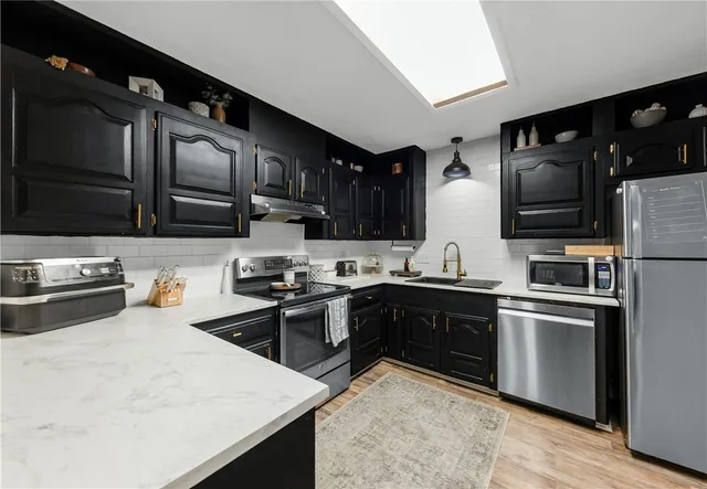 a kitchen with stainless steel appliances granite countertop a stove refrigerator sink and microwave