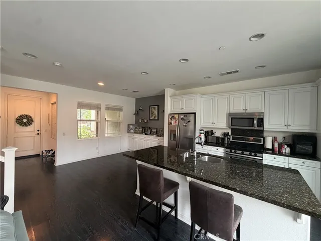 a kitchen with granite countertop a stove a sink a dining table and chairs
