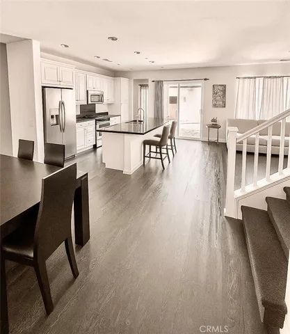 a open kitchen with stainless steel appliances refrigerator dining table and chairs