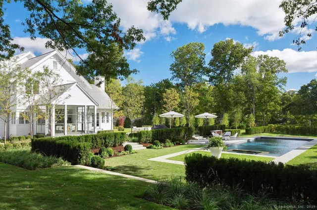 a view of a house with a yard and potted plants and large trees