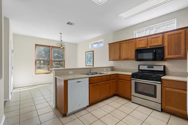 a kitchen with stainless steel appliances granite countertop a stove top oven a sink dishwasher and a refrigerator