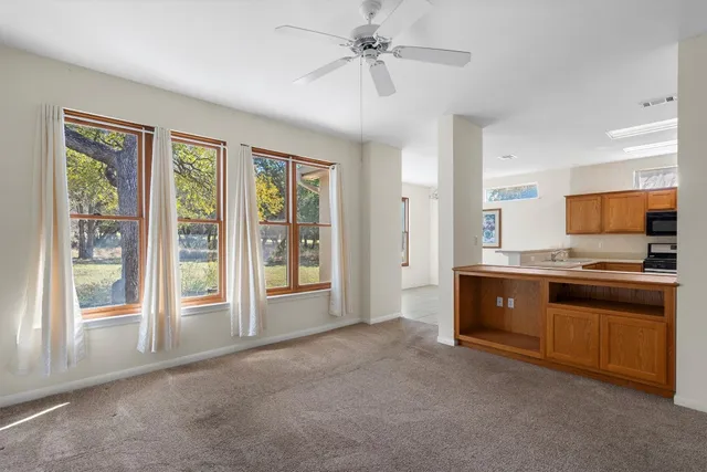 a large white kitchen with granite countertop a stove and a large window