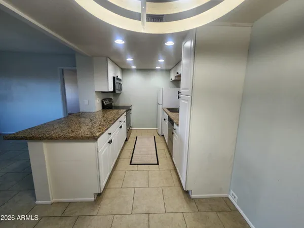 a large kitchen with granite countertop a large counter top and cabinets