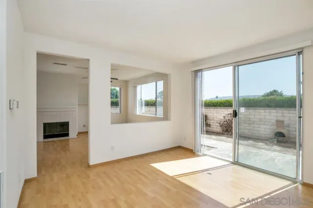an empty room with ceiling fan and kitchen view