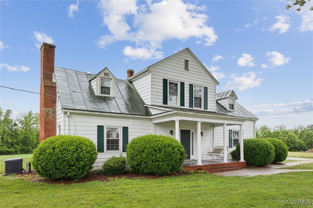 View of front of property featuring a chimney, cov