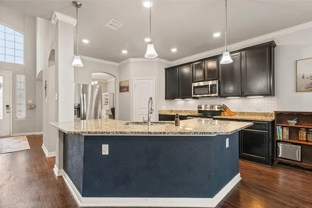 a large kitchen with stainless steel appliances granite countertop a sink a stove and a wooden floors