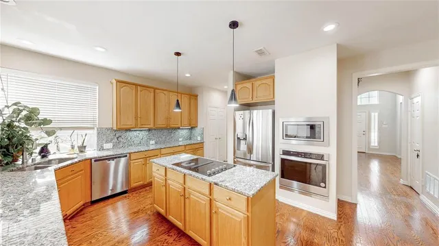 a spacious bedroom with a bed a table and potted plant with the kitchen view