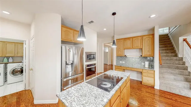 a kitchen with stainless steel appliances granite countertop a sink a counter top space and living room view