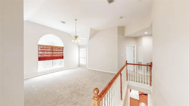 an empty room with chandelier fan and windows